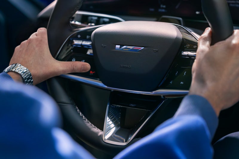 Close-up of a Man About to Press the V-Button on the 2026 OPTIQ-V Steering Wheel | Penske Cadillac of South Bay in Torrance CA