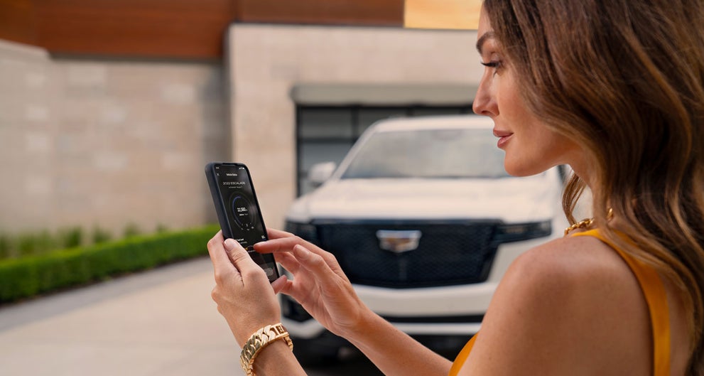 lady checking her mobile with a Cadillac vehicle background | Penske Cadillac of South Bay in Torrance CA